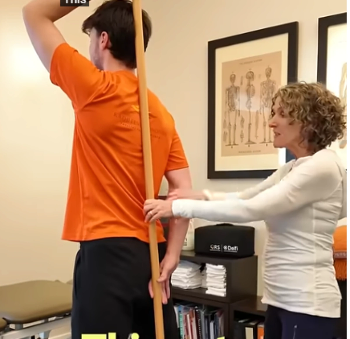 Physical therapist guiding a patient through a posture and alignment exercise using a dowel rod during a physical therapy session for sciatic pain.