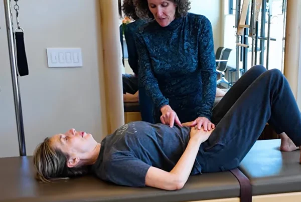 Kathleen McDonough teaching a patient proper breathing techniques to support healthy posture and movement during a physical therapy session.