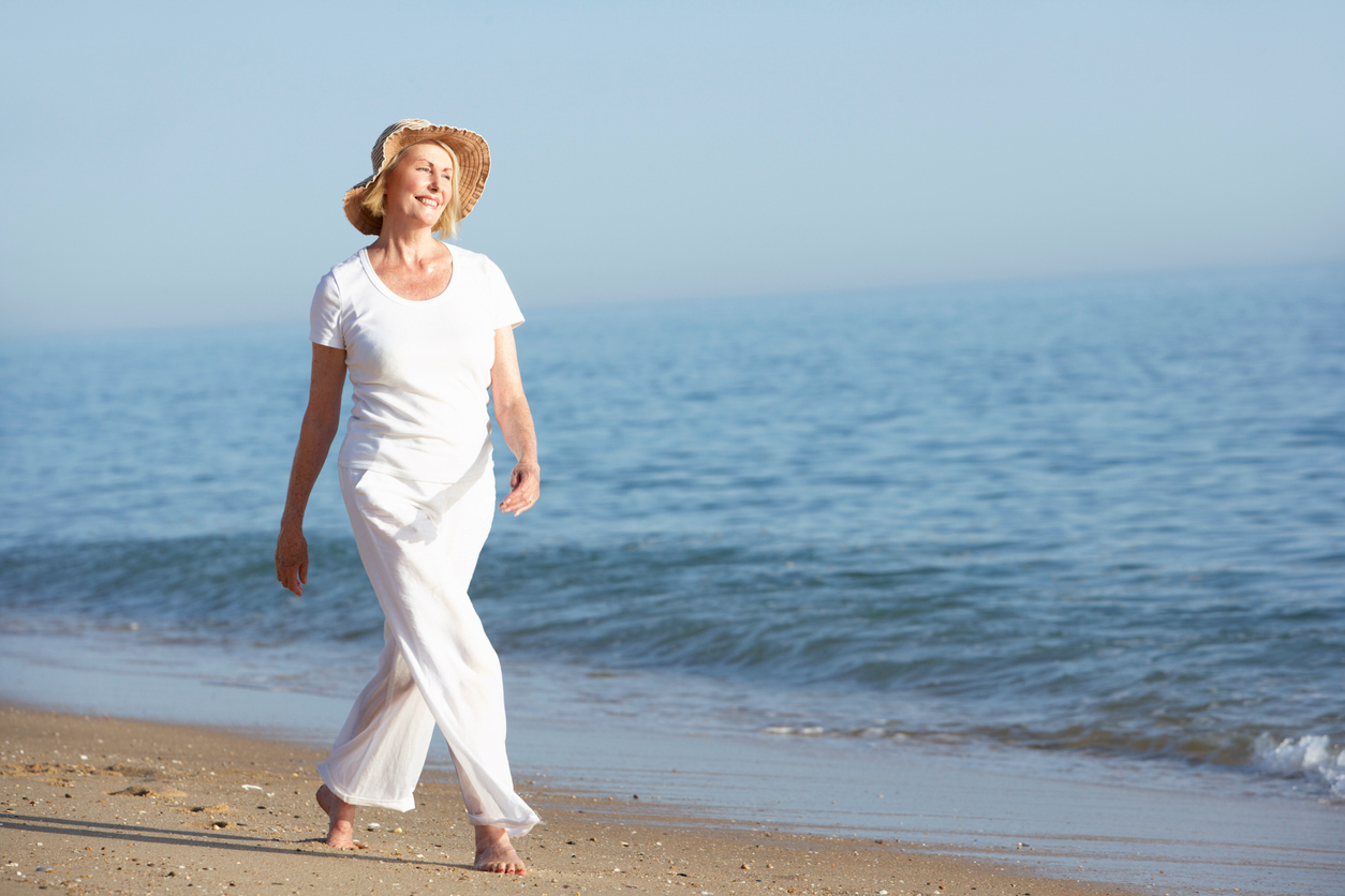 Active older woman walking comfortably along the beach