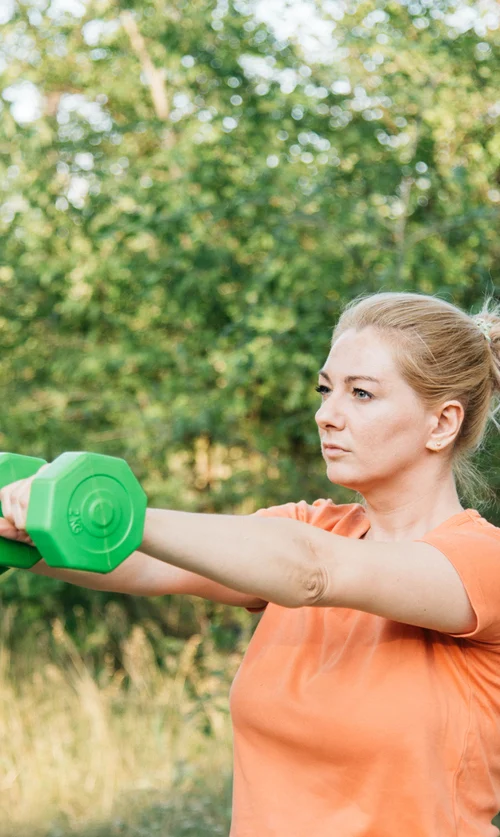 A woman exercising with dumbbells to maintain muscle and strength as she ages.