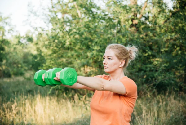 A woman exercising with dumbbells to maintain muscle and strength as she ages.