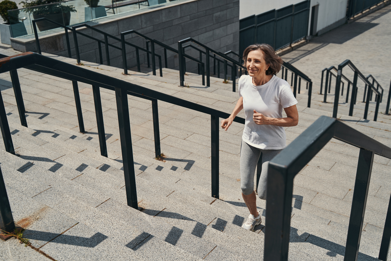 Woman climbing stairs, illustrating the importance of maintaining strength and mobility.